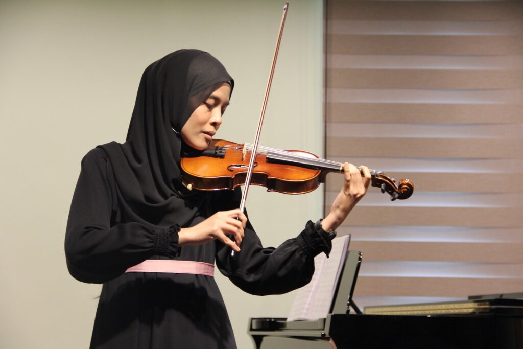 Rose performing violin at the Cephas year-end concert