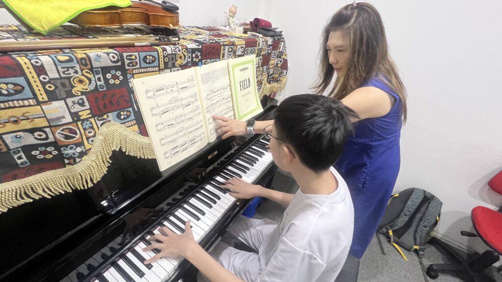Dr. Chendra guiding a young student at the piano