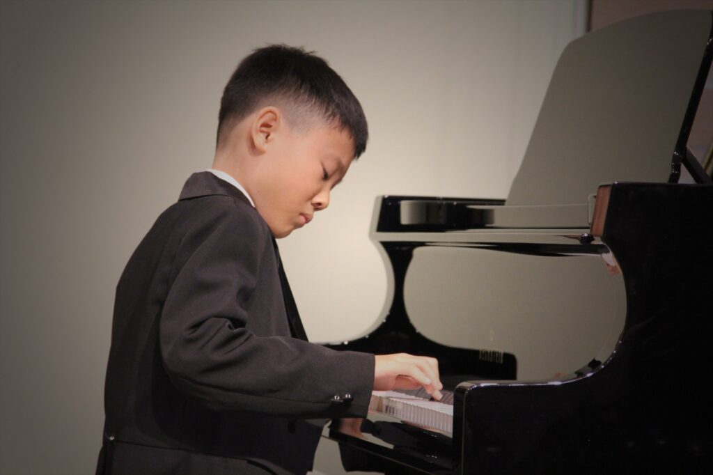 Young piano student playing a grand piano at Cephas Music School